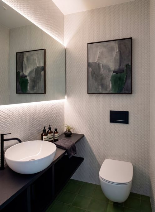 Bagno ospiti con lavabo d'appoggio e specchio retroilluminato
